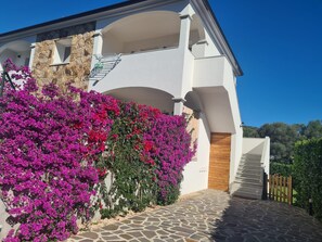 A modern house with a stone facade, a wooden door, and a stone staircase leading to a balcony.