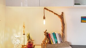 Una habitació amb una làmpada, una planta, un atzavís de fusta i una làmpada de paret.