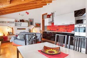 A modern kitchen with white cabinets, a red backsplash, and stainless steel appliances.