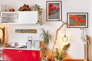 A modern interior with a red cabinet, white shelves, and various decorative items including plants and framed pictures.