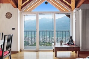 Une chambre avec balcon, une statue de Bouddha et une vue sur la ville et les montagnes.