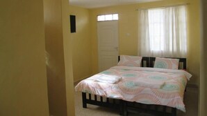 A bedroom with a bed, a window with curtains, and a door.