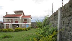 A two-story house with a red roof and a garden in front.