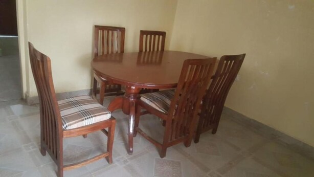 A dining table with four wooden chairs, each with a cushioned seat.