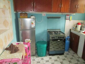 Une cuisine de taille réduite, équipée d’un réfrigérateur, d’une cuisinière et de placards.
