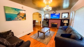 A living room with a fireplace, a television, and a painting on the wall. - New Your Home Away From Home! - Near Great Lakes Naval Base!! (North Chicago)
