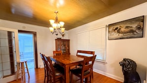 A dining area with a wooden table, chairs, a chandelier, a cabinet, and a lion statue. - New Your Home Away From Home! - Near Great Lakes Naval Base!! (North Chicago)