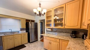 A kitchen with wooden cabinets, a stainless steel refrigerator, a granite countertop, and a chandelier. - New Your Home Away From Home! - Near Great Lakes Naval Base!! (North Chicago)