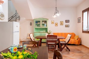 A dining area with a table, chairs, a green cabinet, and a sofa.