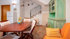 A dining area with a wooden table, chairs, a refrigerator, a cabinet, and a staircase. - Villa 'Brezza di Limoni' close to the Sea with Terraces & A/C (San Vito lo capo)