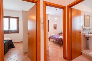 Ein Zimmer mit Bett, Nachttisch, Fenster und einem Badezimmer mit Waschbecken und Spiegel.