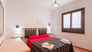 A bedroom with a bed, bedside tables, a desk, a cross on the wall, and a window. - Villa 'Brezza di Limoni' close to the Sea with Terraces & A/C (San Vito lo capo)