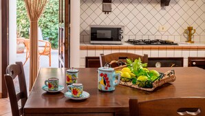 A dining table with a microwave, a basket of lemons, and a clock on the wall. - Villa 'Brezza di Limoni' close to the Sea with Terraces & A/C (San Vito lo capo)