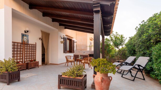 An outdoor patio with wooden furniture, a large planter, and lounge chairs. - Villa 'Brezza di Limoni' close to the Sea with Terraces & A/C (San Vito lo capo)