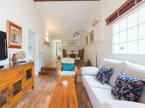 Relax in this open-plan living space featuring a sofa, dining area, and TV.