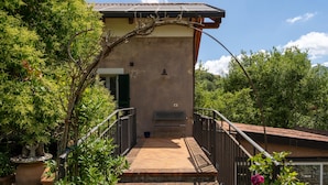 A building with a balcony, surrounded by greenery and a clear sky.