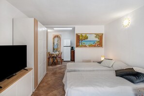 Ett hotellrum med TV, två sängar, en tavla och en matplats.