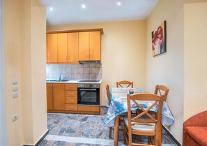 Une cuisine compacte avec des meubles en bois, un four encastré et une table à manger avec des chaises.