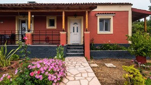 A house with a red facade, a white door, and a stone pathway leading to the entrance.
