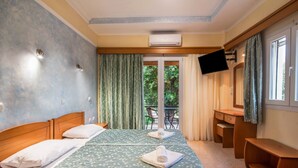 A hotel room with two beds, a desk, a chair, a TV, and a sliding glass door to the outside.
