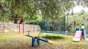A playground with a seesaw, swings, a climbing structure, and a slide.
