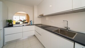 Een moderne keuken met witte kasten, een zwart aanrecht, een roestvrijstalen spoelbak en een raam met uitzicht.