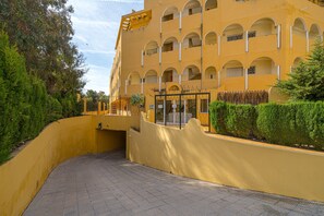 A multi-story hotel with a yellow facade, balconies, and a gated entrance.