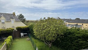 Zona residencial amb un jardí ben cuidat, una tanca de fusta i un gran arbre.
