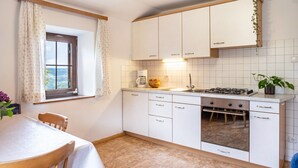 Eine Küche mit weißen Schränken, einem Herd, einem Spülbecken und einem Fenster mit Vorhängen.