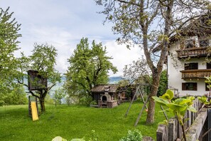 A rustic outdoor setting with a treehouse, a small stone building, and a wooden fence. - Apartment 'Stablerhof - Löwenzahn' with Mountain View, Garden, and Wi-Fi (Cornedo all' isarco)
