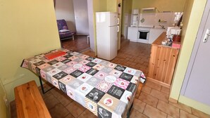 A compact room with a bed, a small kitchenette, and a wooden bench. - Apartment "Doudou Vercors" with Wi-Fi & Terrace (Lans-en-Vercors)