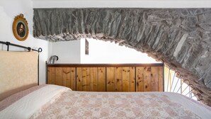 Un dormitorio con cama, cabecera de madera, pared de piedra y un cuadro enmarcado.