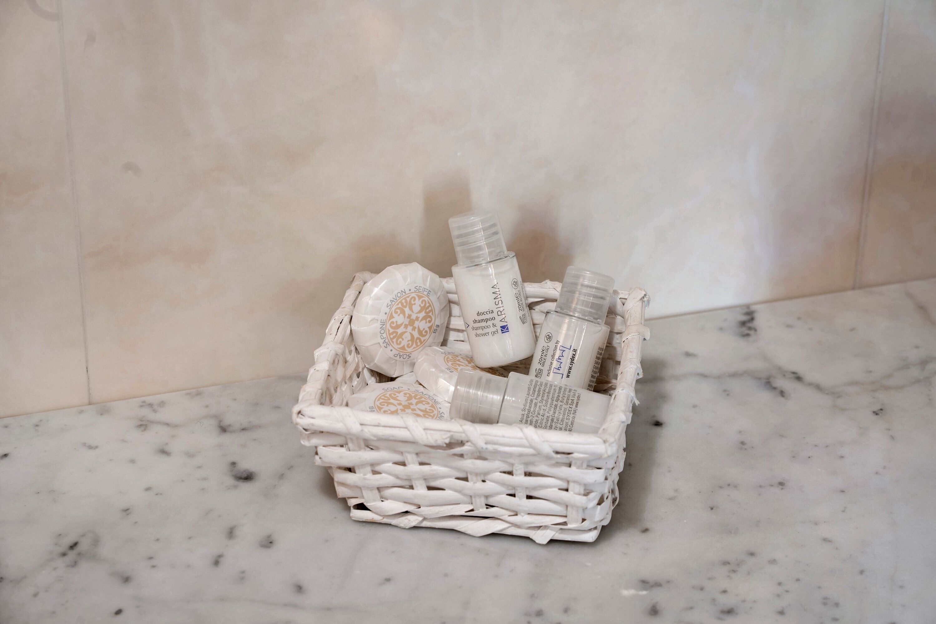 Un panier en osier contenant des articles de toilette, posé sur un sol en marbre.