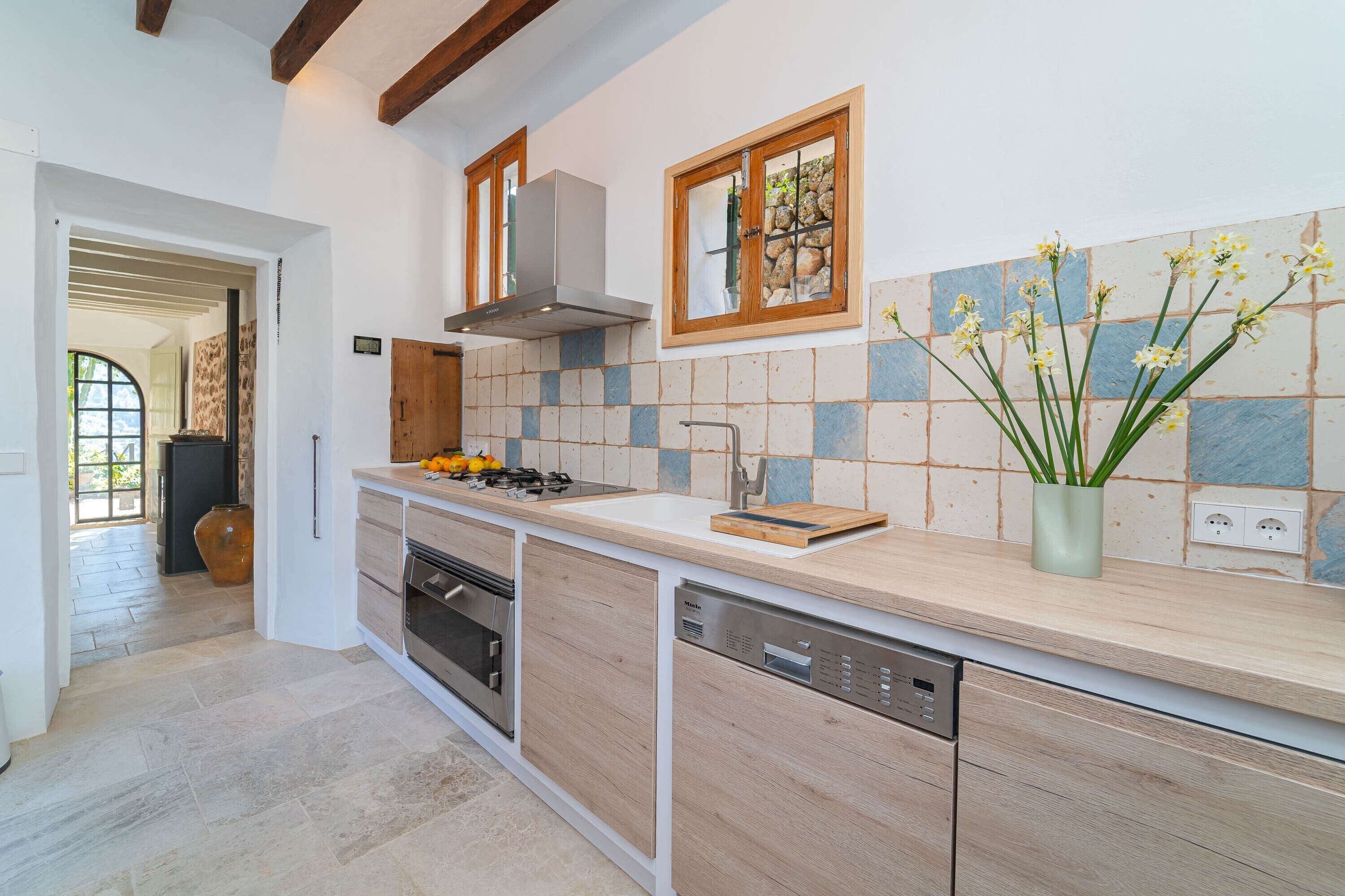 A modern kitchen with a built-in oven, dishwasher, and a window with a view of the outdoors.