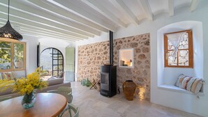 A cozy room with a stone wall, a fireplace, a large vase, and a window seat.
