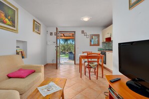 Una sala de estar con sofá, mesa de centro, televisor y un comedor con sillas y mesa.