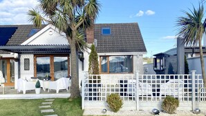 A residential property with a paved driveway, a white fence, and a lawn. - Seaview Cottage on the Island (Islandmagee)