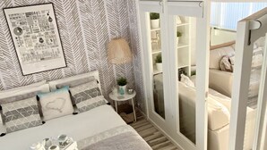 A bedroom with a bed, bedside table, and a door leading to a balcony. - Seaview Cottage on the Island (Islandmagee)