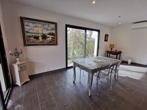 Ein Essbereich mit Tisch und Stühlen, einem Bild an der Wand und Blick durch eine Glastür.