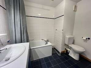 A bathroom with a bathtub, a sink, a toilet, and a shower curtain.