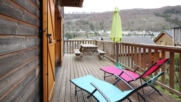 A wooden deck with a picnic table and lounge chairs, overlooking a hilly landscape. - Mont-Dore: 4-bedroom chalet with garage and terrace (Mont-Dore)