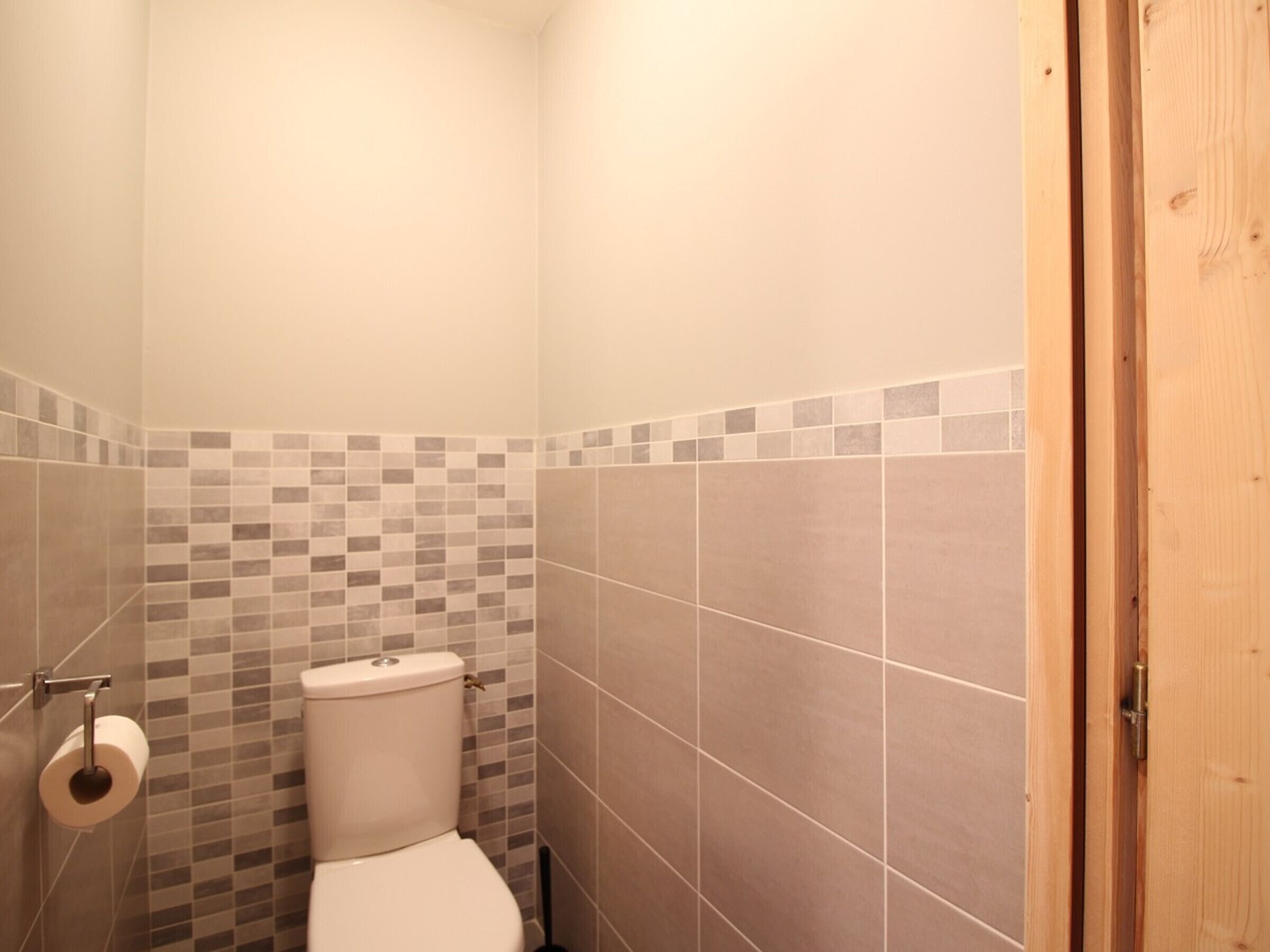 Ein kleines Badezimmer mit Toilette, Toilettenpapier und gefliesten Wänden.