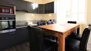 Una cocina moderna con armarios oscuros, una mesa de comedor de madera y sillas negras.