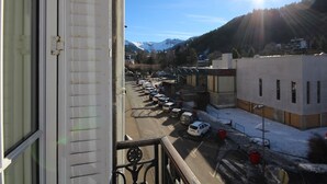 Vista desde una ventana sobre un estacionamiento con coches, un edificio que dice "Casino" y una cadena montañosa al fondo.