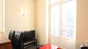Un espacio habitable compacto con televisión de pantalla plana, una mesa de comedor y una mesita de detalles en rojo.