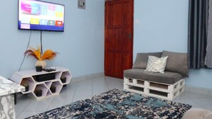 Ein Wohnzimmer mit Fernseher, einer Holztür, einem Sofa und einem gemusterten Teppich.