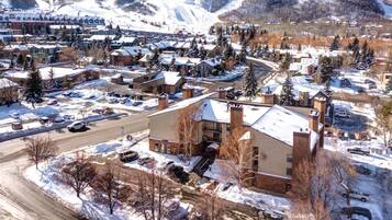 A snow-covered town with multiple buildings, a main road, and a parking area.