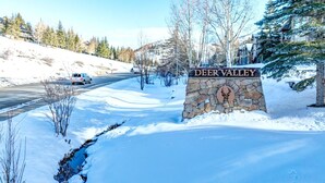A snow-covered landscape with a stone sign reading 'DEER VALLEY' and a deer logo. - Boulder Creek 3 Bedrooms BCC-1101 by KBM (Park City)