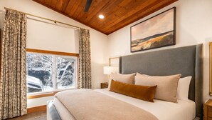 A bedroom with a large bed, a nightstand, a lamp, a window with curtains, and a painting on the wall. - Boulder Creek 3 Bedrooms BCC-1101 by KBM (Park City)