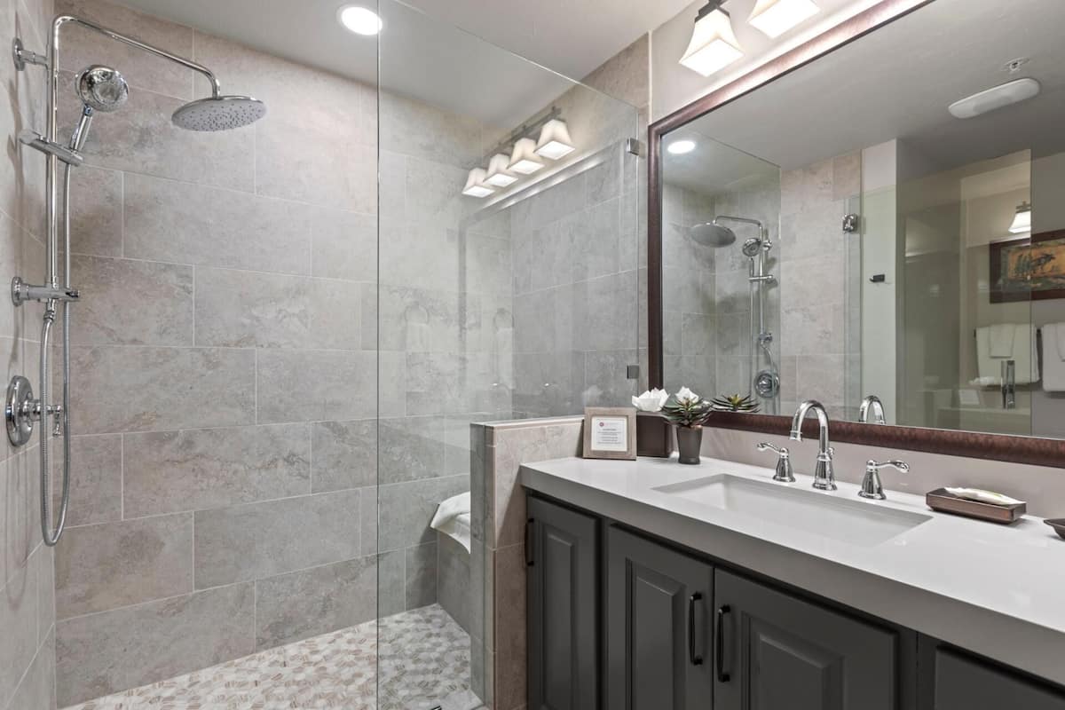 A modern bathroom with a shower, a sink, and a large mirror.